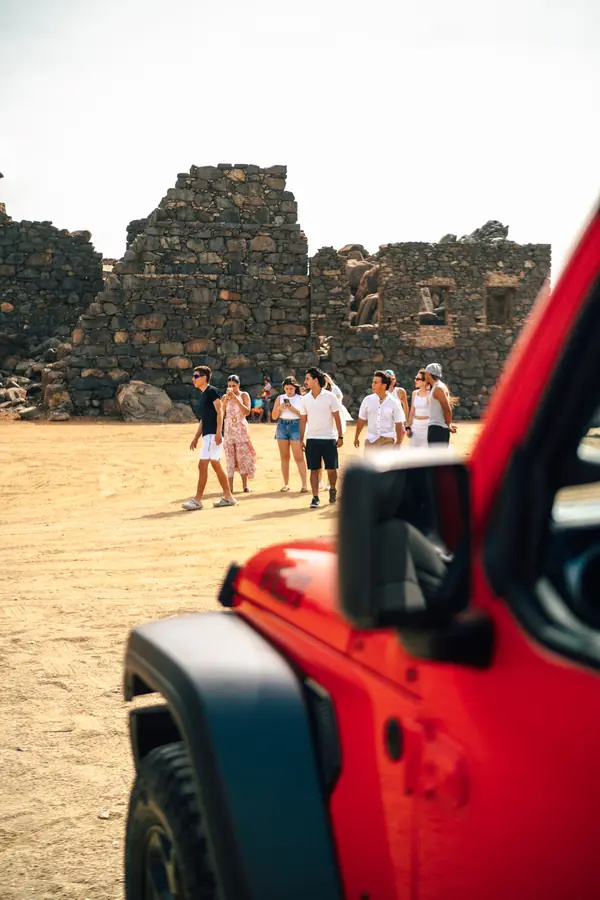 Friends walking at the Bushiribana gold mill ruins next to a rental Jeep